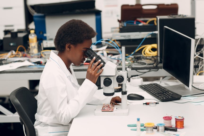 Woman works in a research lab and looks into a microscope
